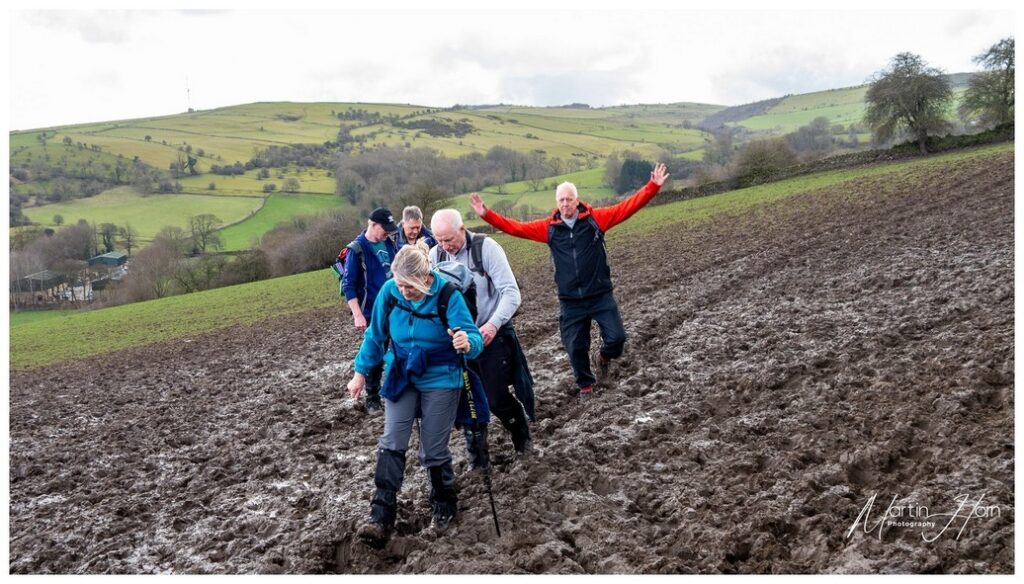 some walkers in a very muddy ploughed field