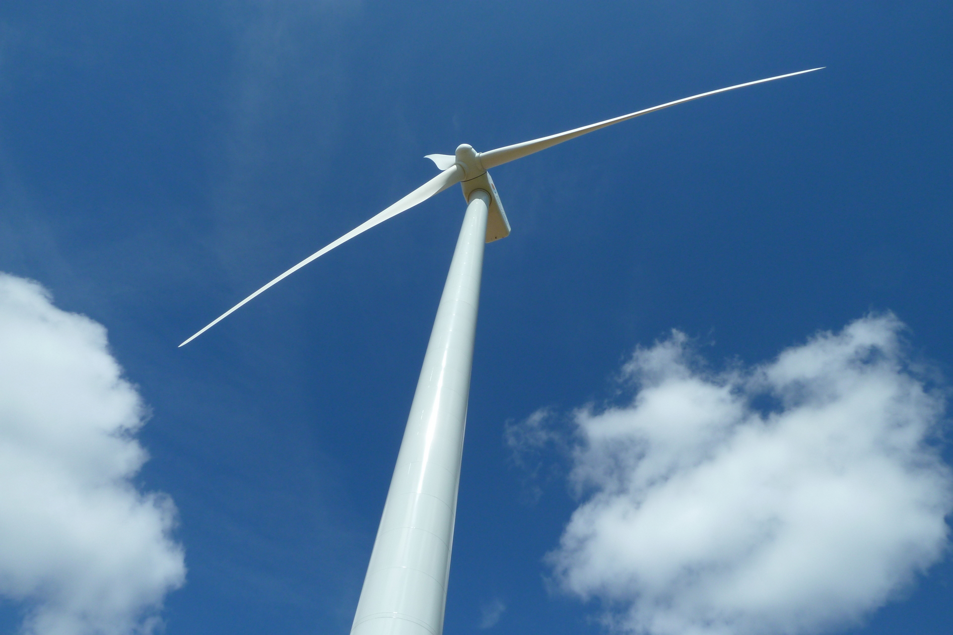a single wind turbine against a blue sky